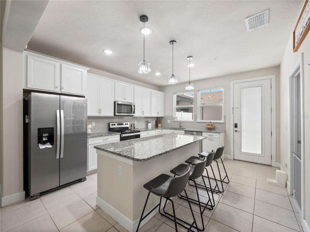 11018 Leafshore Loop Orlando, FL 32829 - Photo 4 of 24 a kitchen with stainless steel appliances granite countertop a refrigerator a sink dishwasher a stove and white cabinets with wooden floor