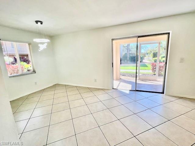 1075 Foxfire Lane, Unit 101 Naples, FL 34104 - Photo 5 of 12 Unfurnished room with light tile patterned flooring, an inviting chandelier, and baseboards
