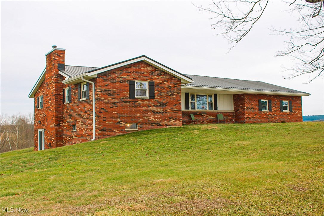 2242 South McCoy Ridge Road Stockport, OH 43787 - Photo 40 of 41 View of front of property with brick siding, a front yard, a chimney, and a metal roof