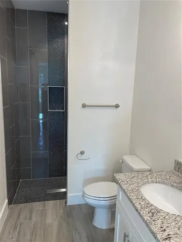 a bathroom with a granite countertop sink a toilet and shower