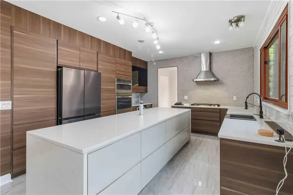a large kitchen with stainless steel appliances a large counter top a stove and a refrigerator