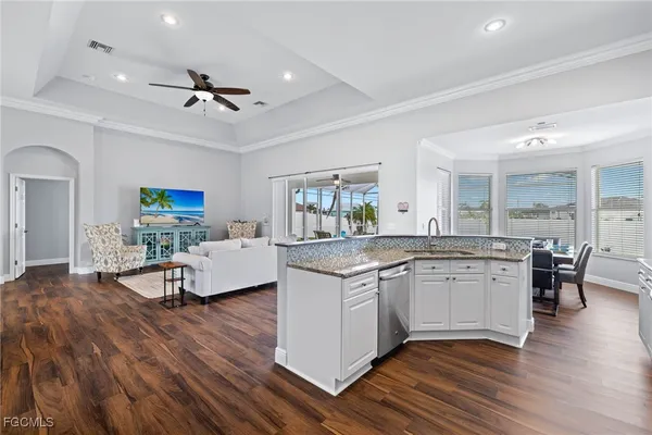 a open kitchen with stainless steel appliances granite countertop a stove and chairs with wooden floor