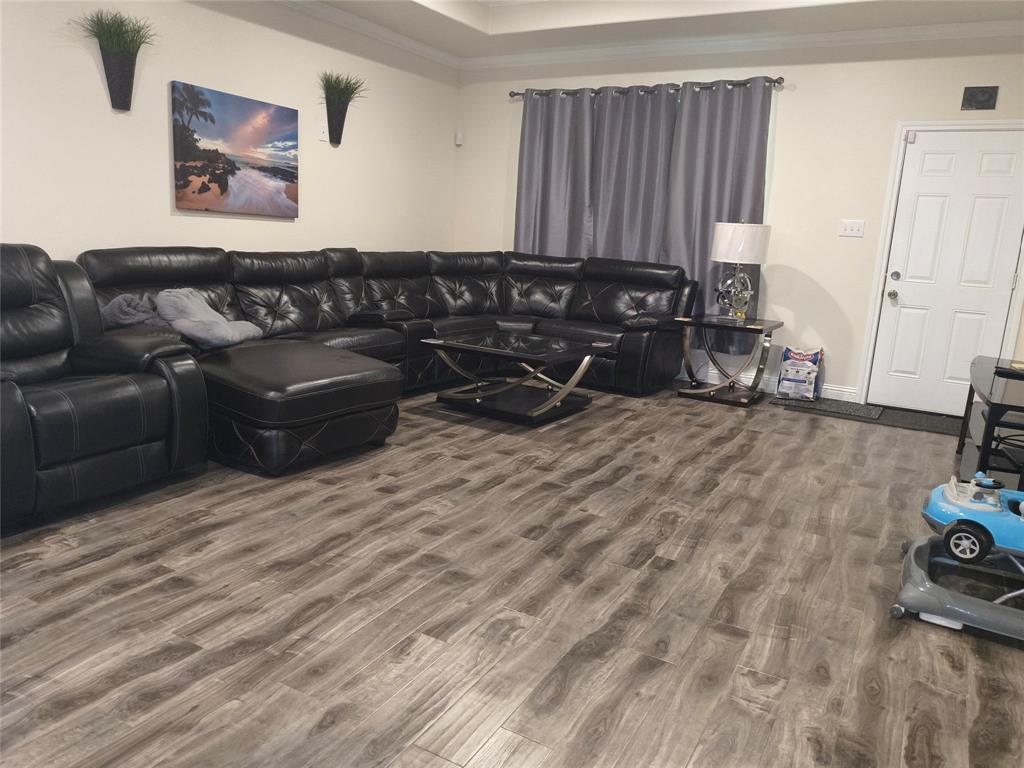 Spacious room featuring wood-finish flooring, light neutral wall paint, and a white paneled entry door