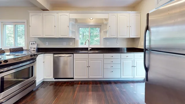 a kitchen with granite countertop white cabinets and stainless steel appliances