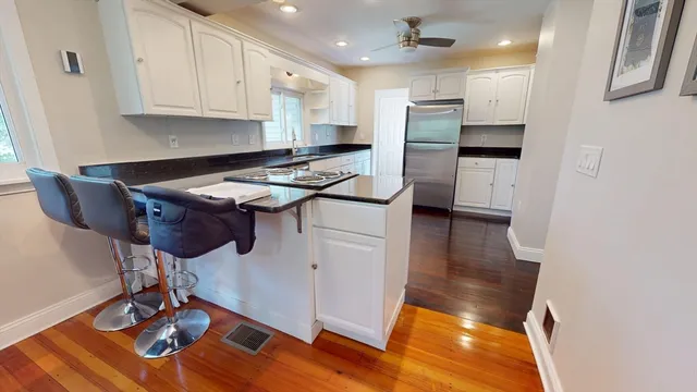 a kitchen with kitchen island stainless steel appliances a stove a sink a refrigerator wooden floor and cabinets