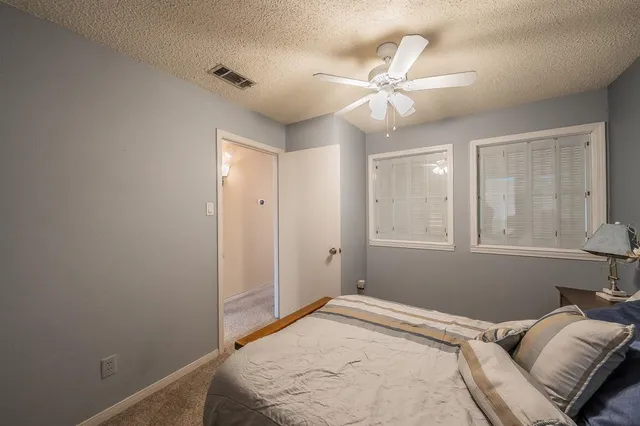 a bedroom with a large bed and a chandelier fan