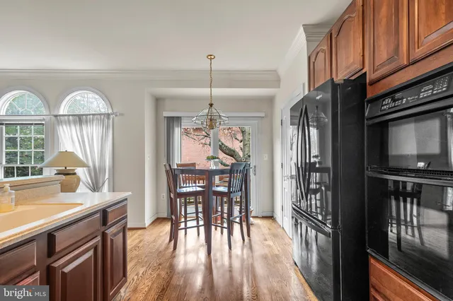 a kitchen with stainless steel appliances granite countertop a stove top oven a sink dishwasher a dining table and chairs with wooden floor