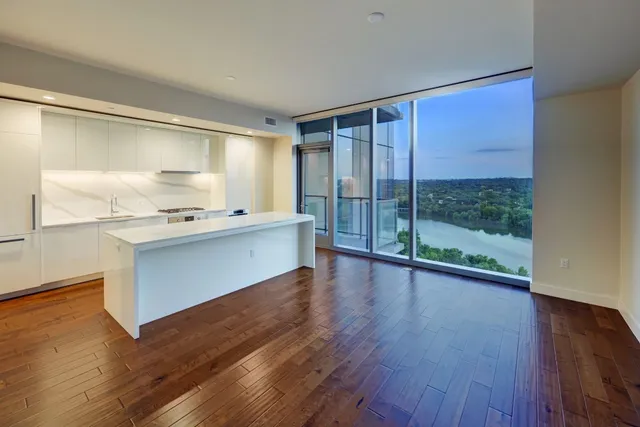 a room with kitchen island granite countertop wooden floors and wide window