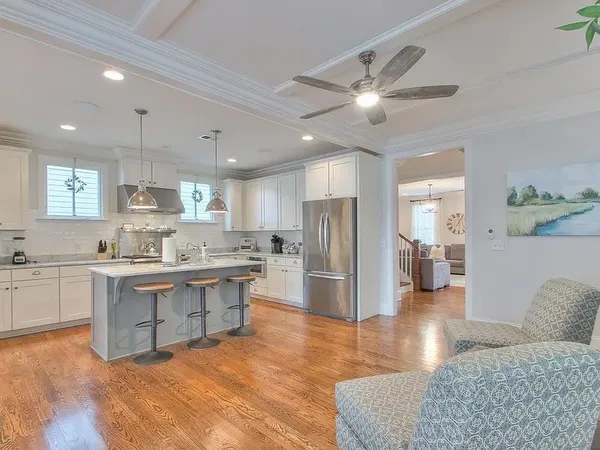 a kitchen with stainless steel appliances granite countertop a refrigerator a sink dishwasher a stove and white cabinets with wooden floor