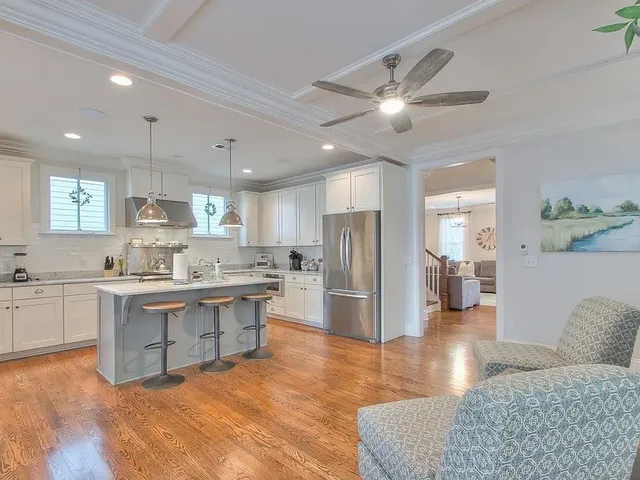 a kitchen with stainless steel appliances granite countertop a refrigerator a sink dishwasher a stove and white cabinets with wooden floor