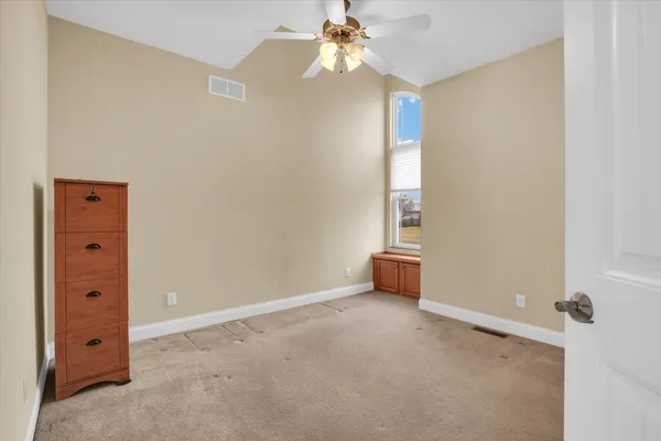 an empty room with a window and a ceiling fan