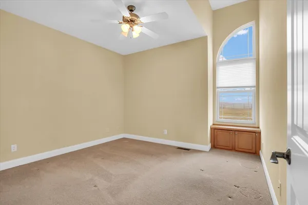 an empty room with windows and chandelier fan
