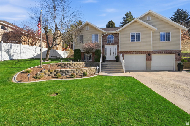 Split foyer home featuring brick siding, an attached garage, and concrete driveway