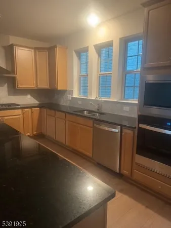 a kitchen with stainless steel appliances granite countertop a sink a stove cabinets and a refrigerator