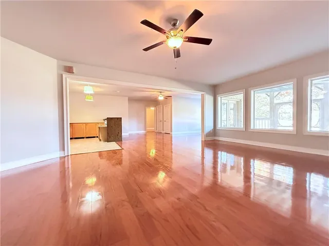 a view of an empty room with a window and wooden floor