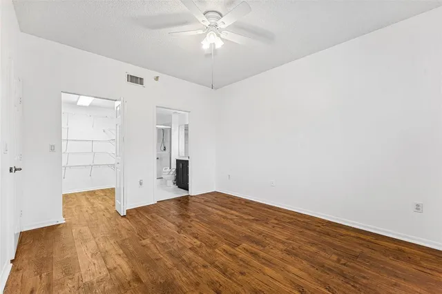 a view of empty room with wooden floor and fan