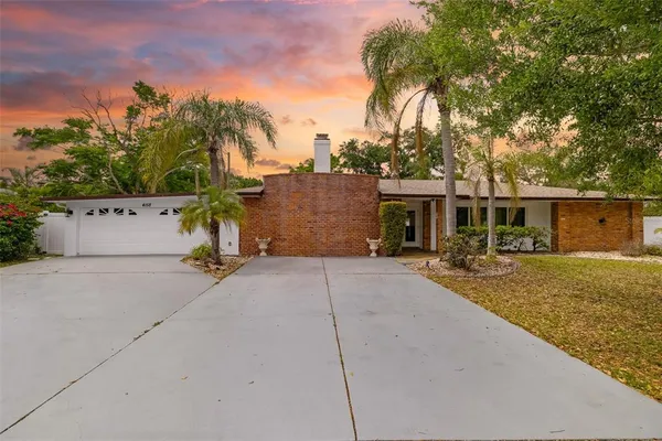 front view of house with a yard and a trees in the background