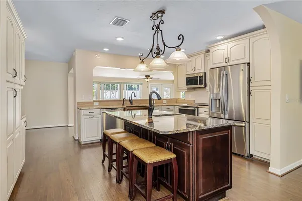 a kitchen with stainless steel appliances granite countertop a sink a stove and a wooden floors