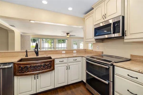 an empty room with wooden floor kitchen view and windows