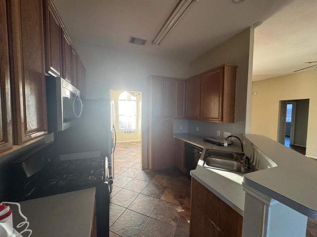 1805 Whirlwind Trail Round Rock, TX 78664 - Photo 11 of 17 Kitchen with stone tile flooring, gas stove, stainless steel microwave, a peninsula, and dishwasher