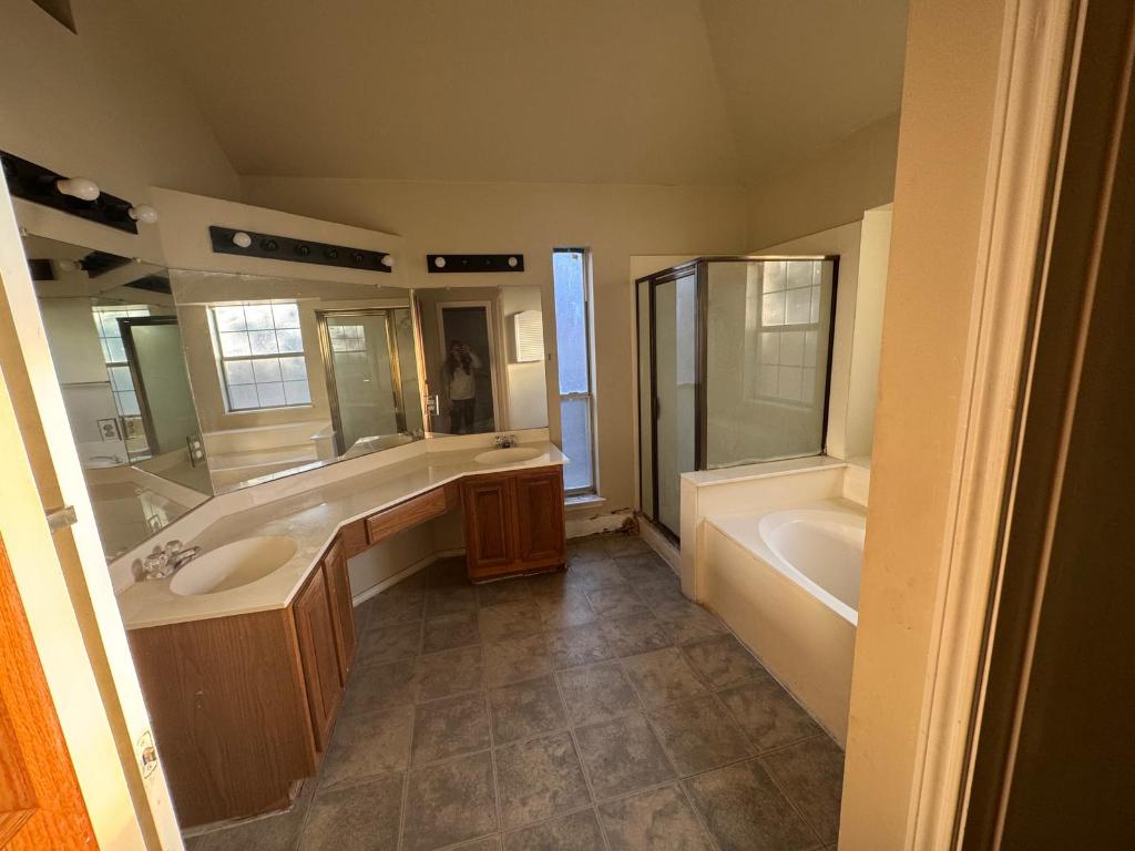 1805 Whirlwind Trail Round Rock, TX 78664 - Photo 15 of 17 Bathroom featuring a bath, double vanity, a stall shower, and vaulted ceiling