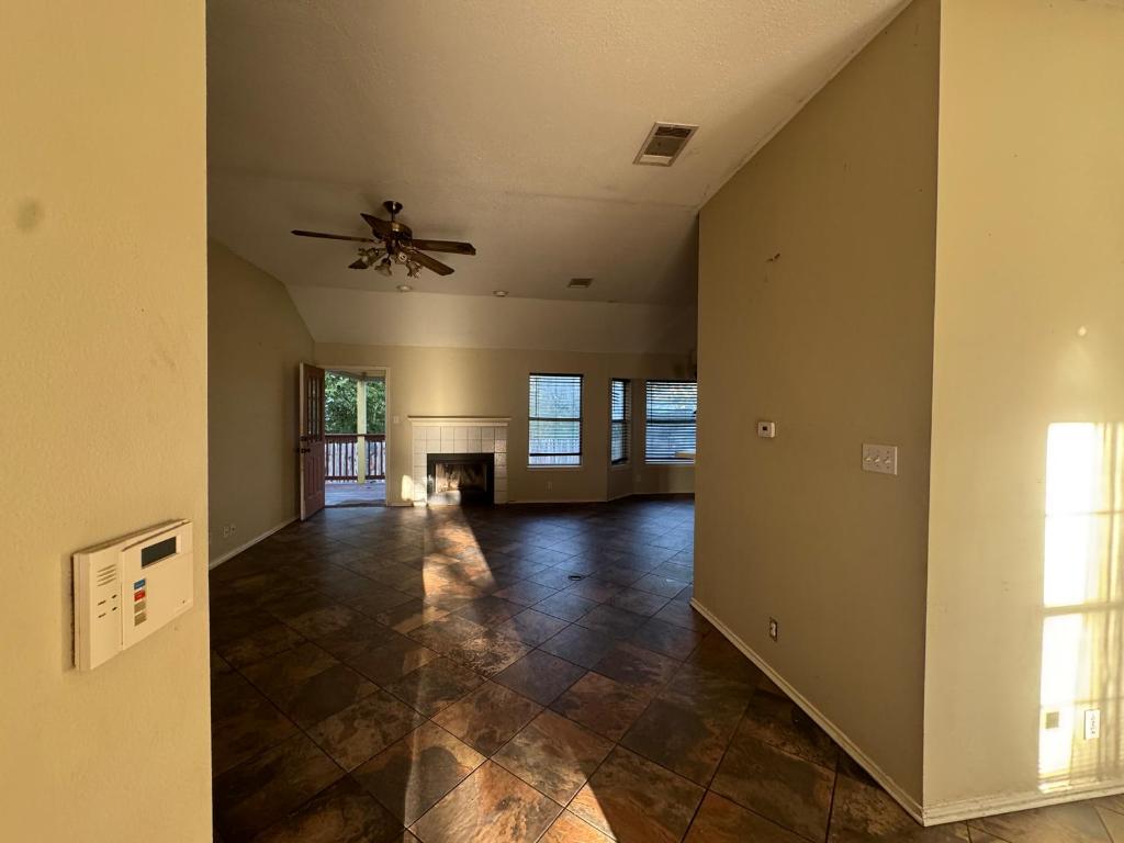 1805 Whirlwind Trail Round Rock, TX 78664 - Photo 4 of 17 Spare room featuring vaulted ceiling, a tile fireplace, a ceiling fan, and dark stone finish floors