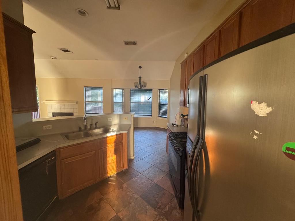 1805 Whirlwind Trail Round Rock, TX 78664 - Photo 8 of 17 Kitchen with black appliances, vaulted ceiling, light countertops, a peninsula, and stone tile floors