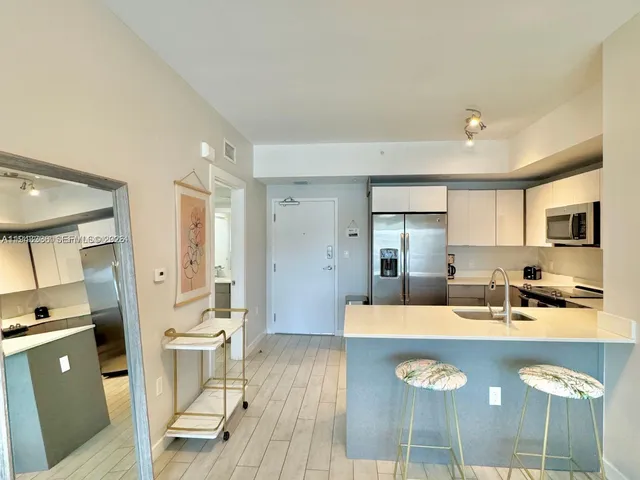 a kitchen with stainless steel appliances granite countertop a stove a sink dishwasher and a refrigerator with wooden floor