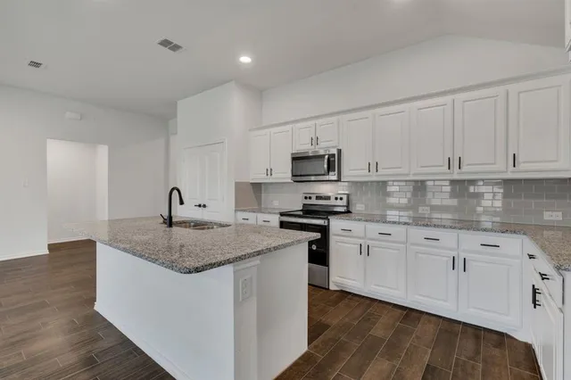 a large kitchen with stainless steel appliances granite countertop a sink and cabinets