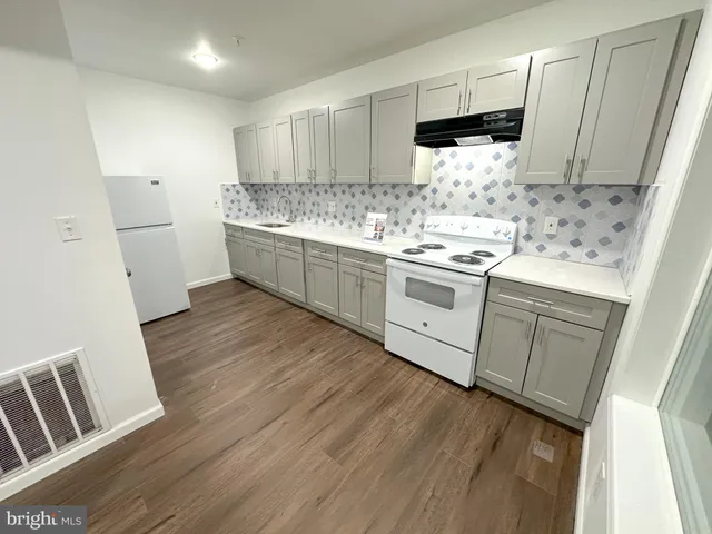 a kitchen with stainless steel appliances a white cabinets sink and wooden floor