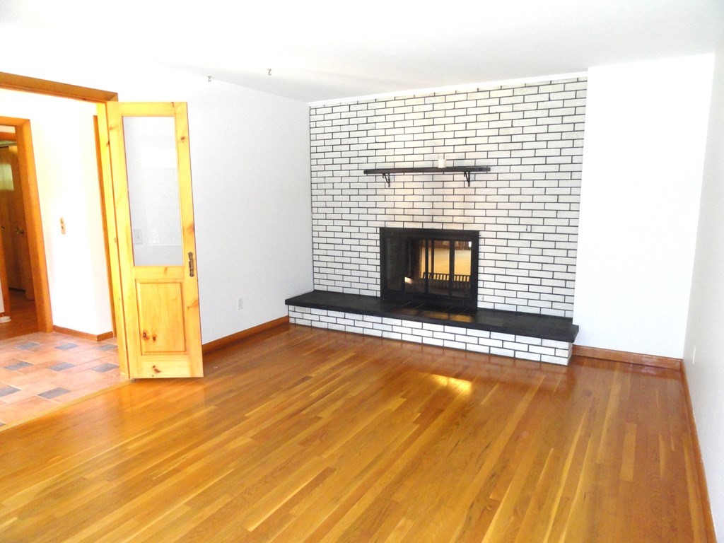88 Charlton Road Dudley, MA 01571 - Photo 5 of 40 a view of empty room with wooden floor and fireplace