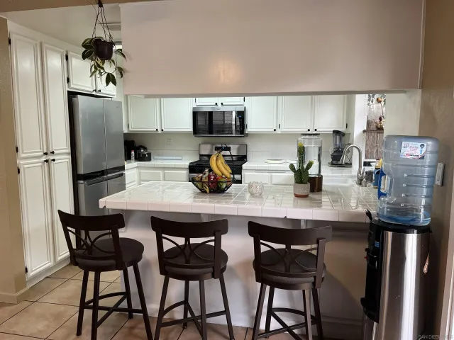 a kitchen with stainless steel appliances granite countertop a dining table chairs refrigerator and cabinets