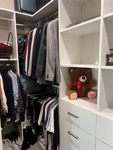 a view of walk in closet with clothes and shoes