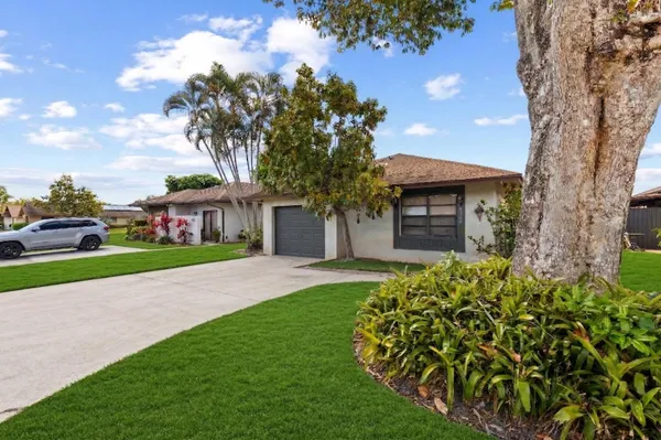 a front view of a house with a garden and trees