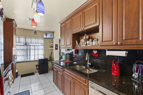 a kitchen with granite countertop a sink dishwasher stove and cabinets
