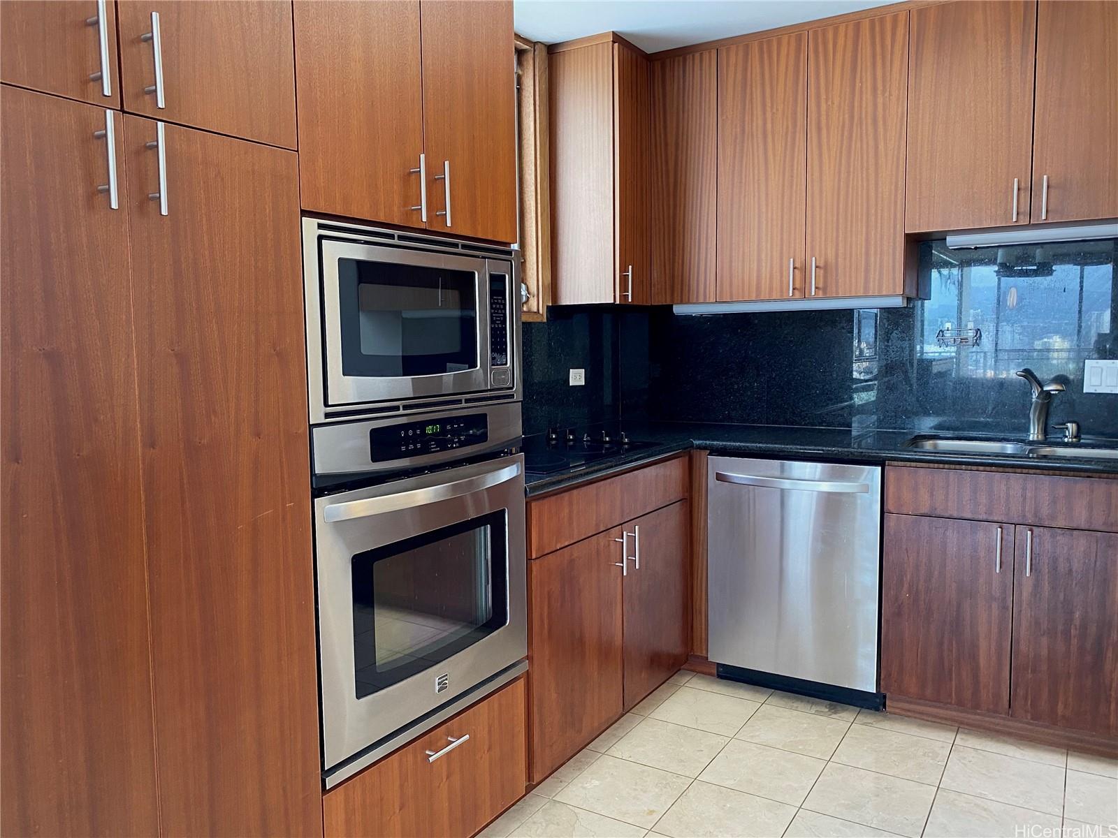 1717 Ala Wai Boulevard, Unit 2101 Honolulu, HI 96815 - Photo 1 of 1 a kitchen with granite countertop a stove top oven microwave and cabinets