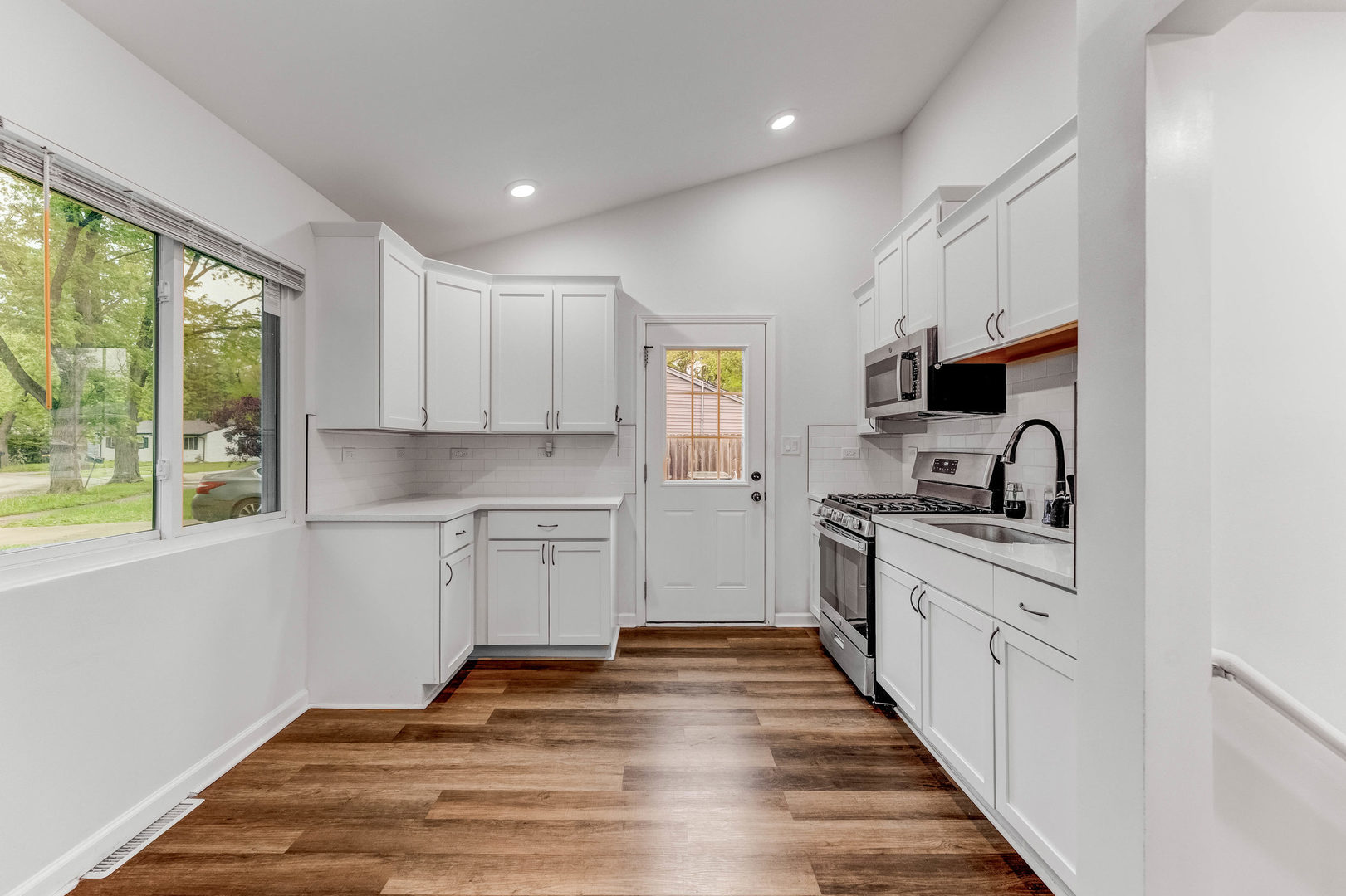 15331 Cherry Lane Markham, IL 60428 - Photo 7 of 23 a kitchen with granite countertop white cabinets a sink a window and stainless steel appliances