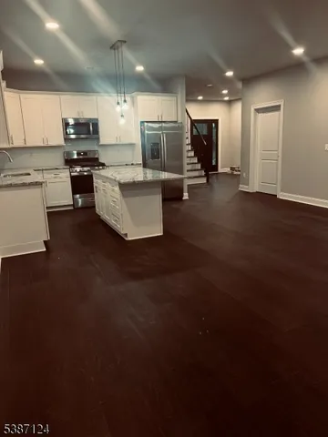 a view of kitchen with kitchen island stainless steel appliances sink refrigerator and microwave