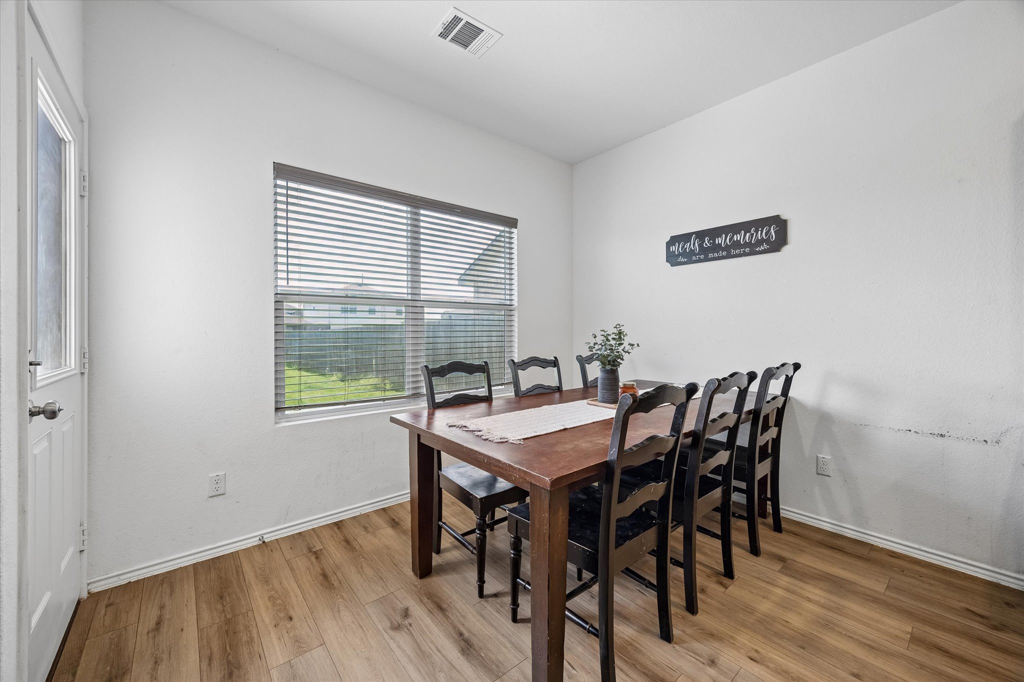 217 Canley Loop Hutto, TX 78634 - Photo 8 of 36 Hardwood-style flooring extends through this bright dining area, featuring a large window with horizontal blinds.