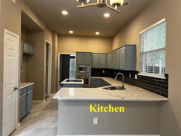a kitchen with kitchen island granite countertop a sink a counter top space stainless steel appliances and a window