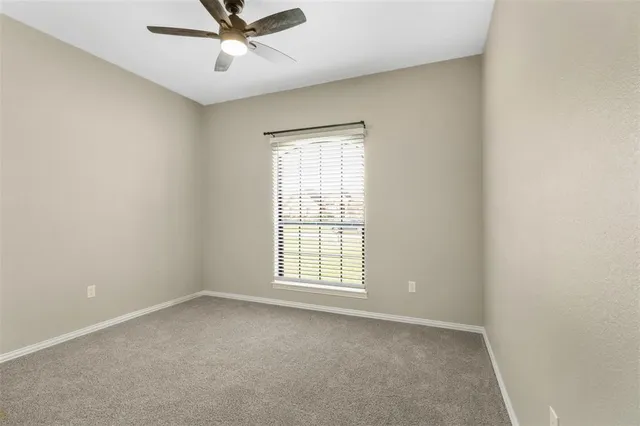 an empty room with a window and a fan