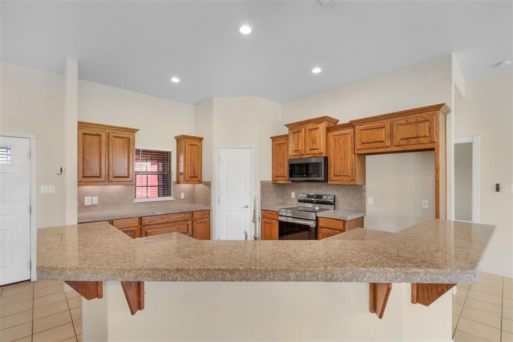 2833 Willow Ridge Circle Granbury, TX 76049 - Photo 10 of 23 a kitchen with stainless steel appliances granite countertop a sink and a refrigerator