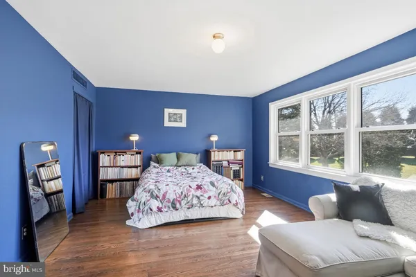 a spacious bedroom with a bed and wooden floor
