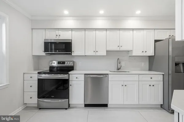 a kitchen with stainless steel appliances a stove a sink a microwave a refrigerator and cabinets