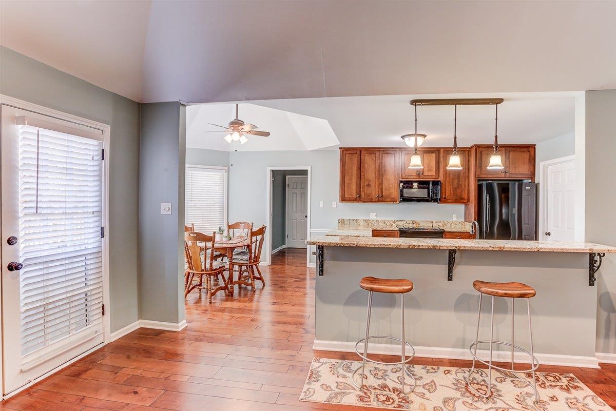665 Lancelot Lane Collierville, TN 38017 - Photo 9 of 26 a kitchen with stainless steel appliances granite countertop a stove top oven a sink a dining table and chairs with wooden floor