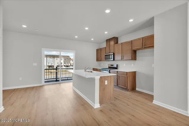 a kitchen with stainless steel appliances kitchen island wooden cabinets and wooden floor