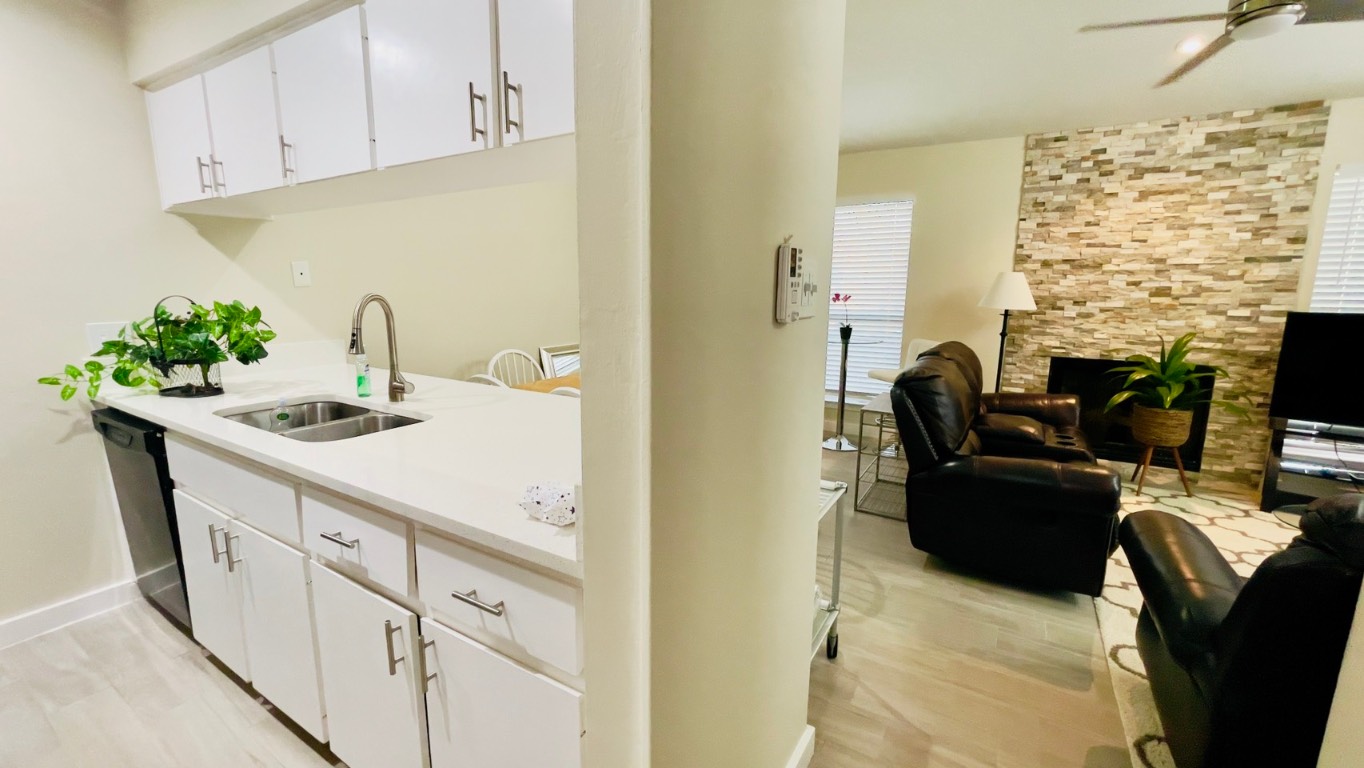 2902 Cole Street, Unit 311 Austin, TX 78705 - Photo 7 of 16 Kitchen with white cabinets, a fireplace, light wood finished floors, ceiling fan, and dishwasher