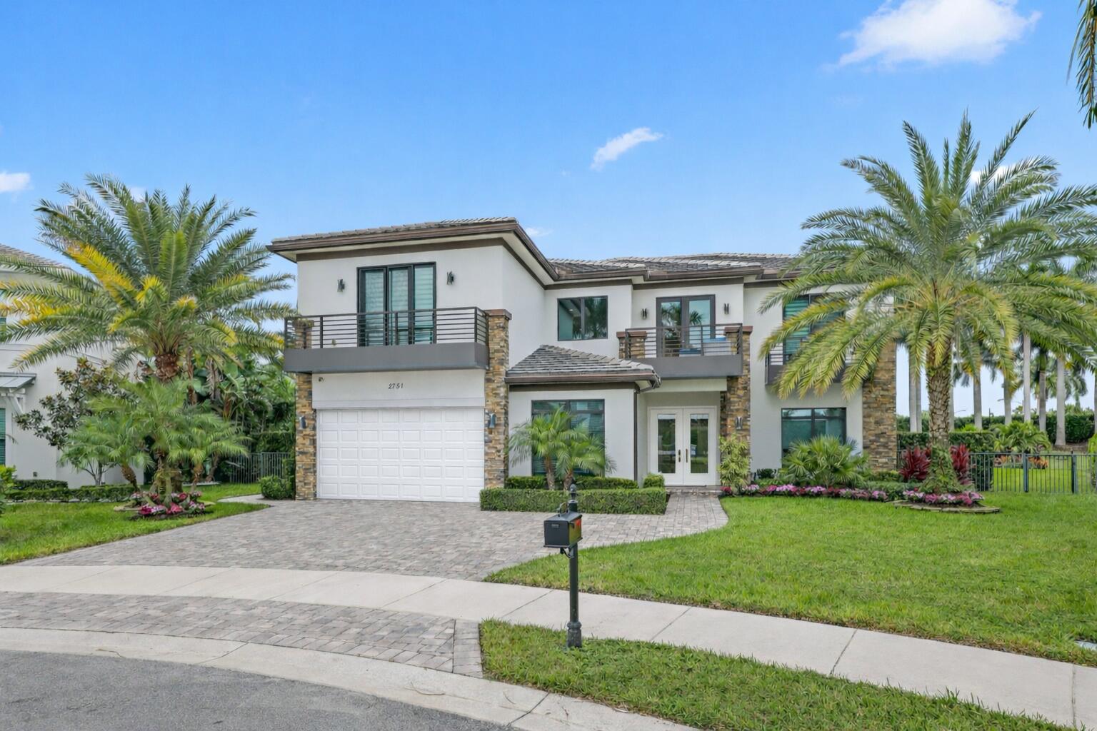 a front view of a house with a garden and palm trees