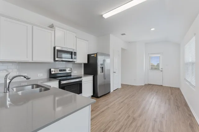 a kitchen with stainless steel appliances granite countertop a stove top oven a sink and white cabinets