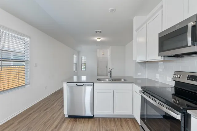 a kitchen with white cabinets and stainless steel appliances